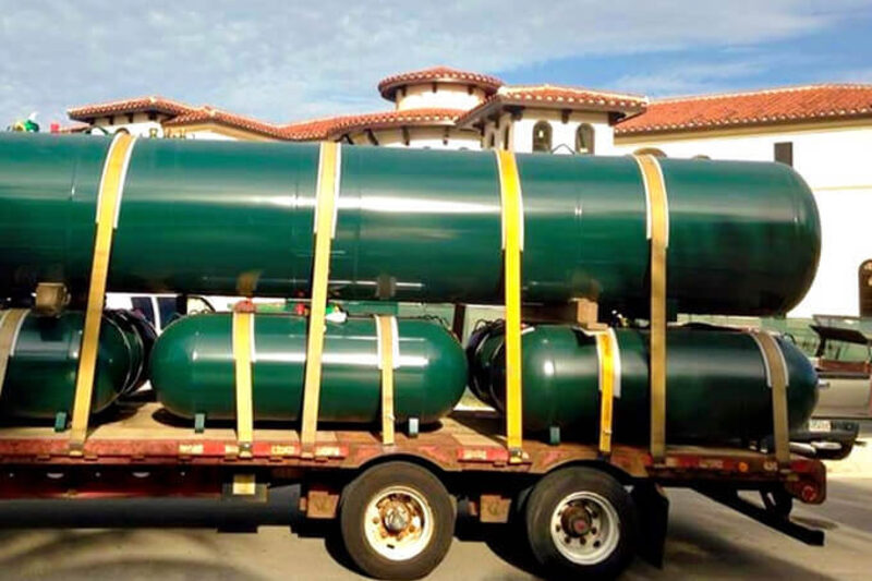 Large propane tanks strapped to a flatbed for delivery.