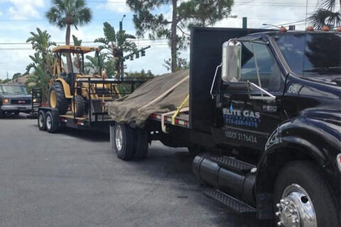 An Elite Gas flatbed truck hauling equipment to a job site.
