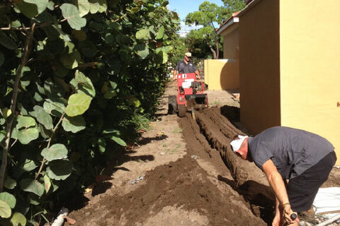 An Elite Gas technician running a gas line alongside a home.